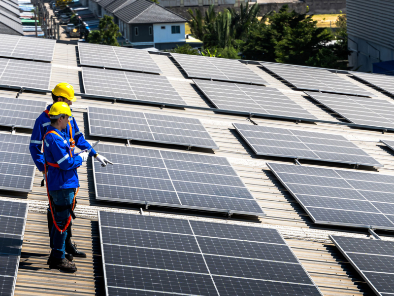 two people working on a roof with solar panels attached