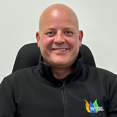 Person with no hair, smiling and wearing a fleece.