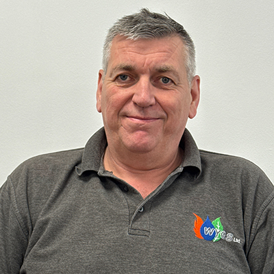 Person with short grey hair wearing a grey WYGS polo top